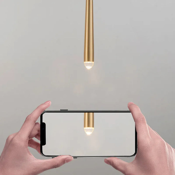 Une main tenant un téléphone avec une lumière qui en émane, une suspension conique allongée en cuivre style moderne industriel. Disponible en deux tailles, 40 ou 50 cm, avec une ampoule LED de 7W pour un éclairage optimal de 3-5 m².