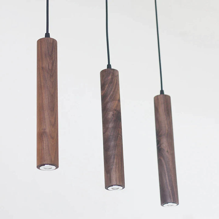 Suspension bois noyer triple cylindres minimalistes design scandinave, éclairage doux et chaleureux pour une atmosphère accueillante.