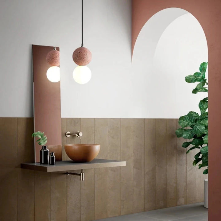 Suspension en verre double globe terrazzo design scandinave, éclairant une salle de bain avec un lavabo et un miroir.