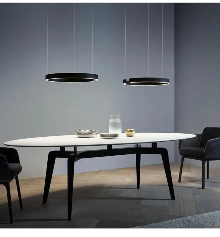 Une table à manger avec des chaises dans une pièce, avec une suspension métal anneau ouvert design moderne suspendue au-dessus.