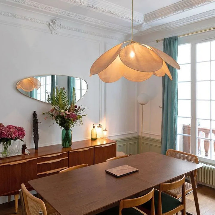 Suspension tissu fleur pétales design vintage bohème éclairant une salle à manger avec une table et des chaises.