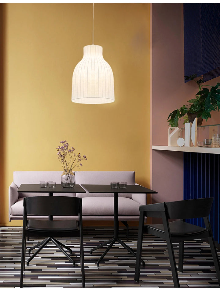 Une table et des chaises dans une pièce avec une suspension cloche rayée en soie minimaliste scandinave suspendue au-dessus de la table.