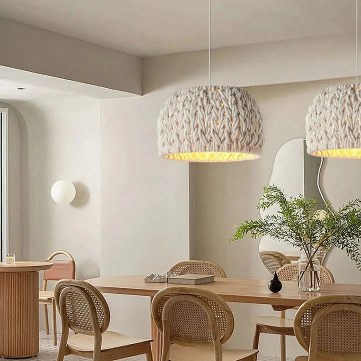 Une salle à manger avec une table et des chaises, une suspension cloche en corde tressée design scandinave suspendue au plafond.