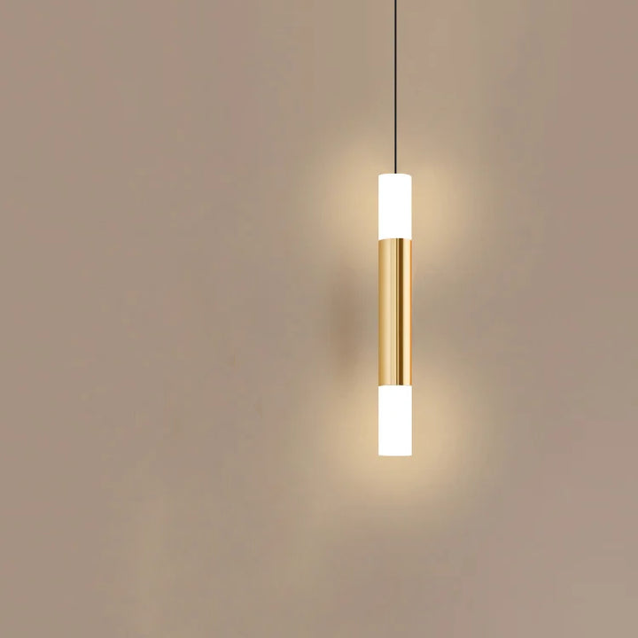 Suspension laiton doré cylindrique moderne avec lumière chaleureuse aux extrémités. Parfait pour un décor moderne ou classique. Ampoule incluse.
