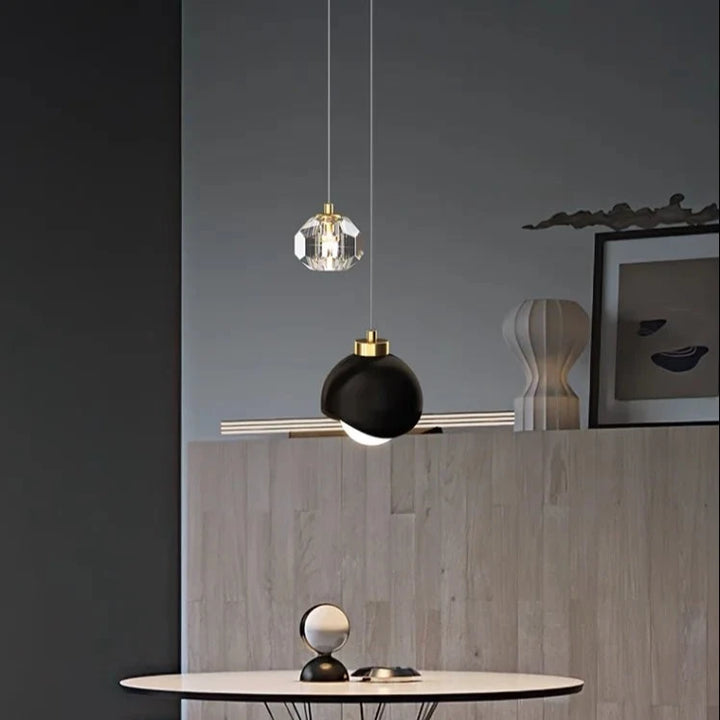 Suspension LED double moderne cristal boule sur table ronde, avec deux lampes, cadre blanc sur chaise, horloge, chapeaux sur mur, lampe noire et dorée.