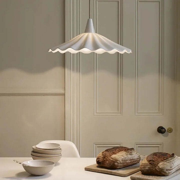 Suspension en céramique blanche ondulée vintage éclairant une table avec des bols et des pains