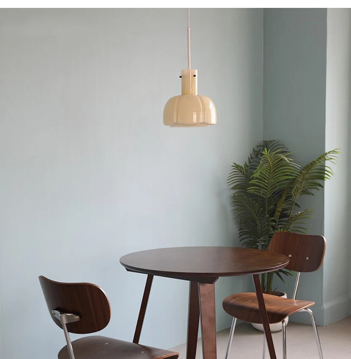 Une table et des chaises dans une pièce avec une suspension verre fumé fleur vintage suspendue au-dessus de la table.