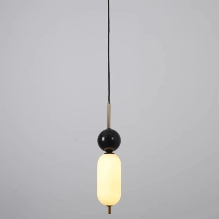 Suspension moderne bicolore avec boule noire sur marbre, lampe de plafond élégante.