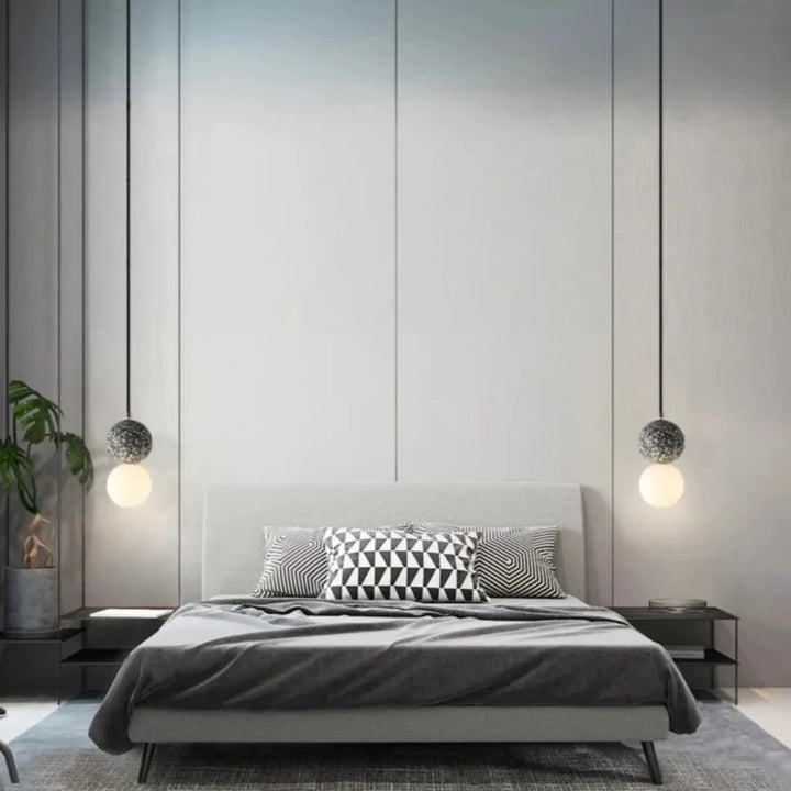 Une chambre avec un lit et une plante, suspension en verre double globe terrazzo design scandinave.