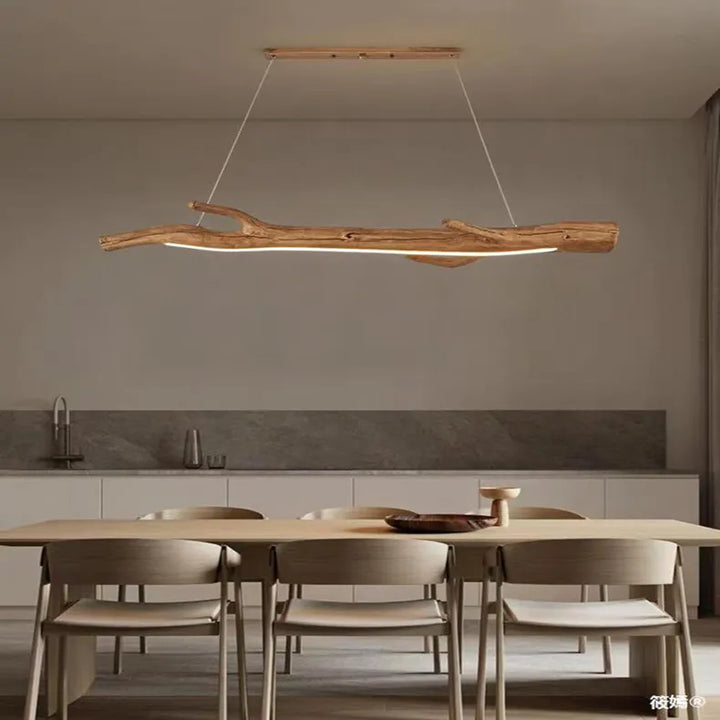 Suspension bois branche design bohème dans une salle à manger avec chaise et table. Ambiance chaleureuse et accueillante grâce à sa branche imposante dotée de LED intégrées. Parfait pour un style bohème ou éco-chic.