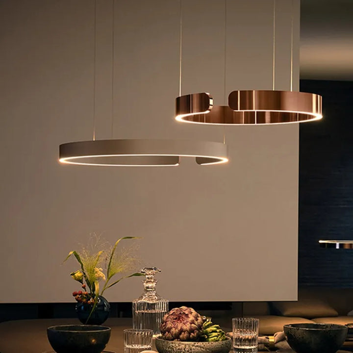 Suspension métal anneau ouvert design moderne éclairant un espace intérieur avec élégance et style. Disponible en différentes finitions luxueuses, cette suspension circulaire diffuse une lumière LED polyvalente. Parfaite pour créer un point focal dans votre salon ou cuisine. Ampoule LED incluse.