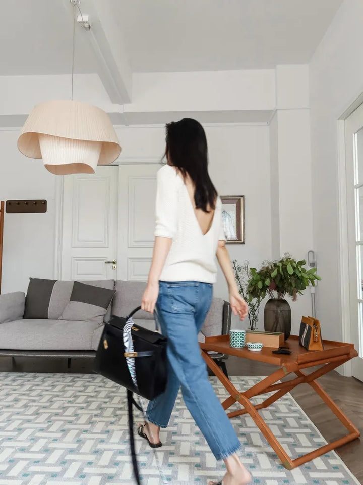 Une femme marchant dans un salon avec une suspension tissu double vague design moderne de LampeSuspension.com.