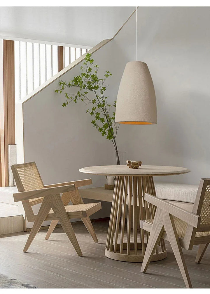 Une table et des chaises dans une pièce avec une suspension cloche allongée effet terre cuite beige bohème suspendue au-dessus de la table.