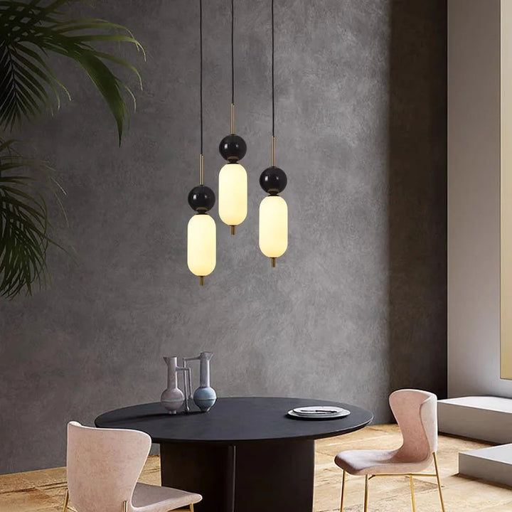 Une table avec des chaises et un lustre, mettant en valeur la Suspension moderne bicolore boule noire marbre de LampeSuspension.com.