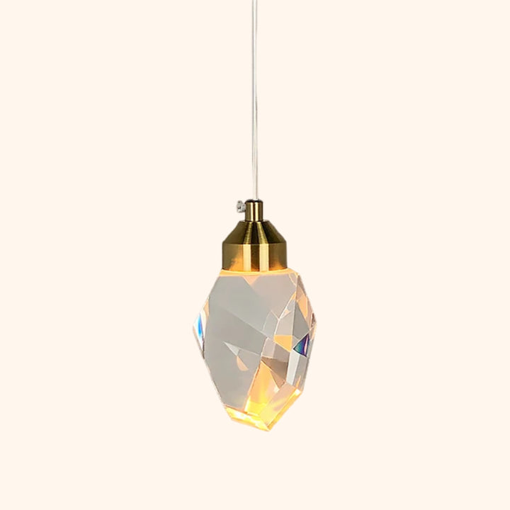 Une suspension avec LED intégré en forme de pierre de cristal avec base dorée est montrée sur fond beige. 