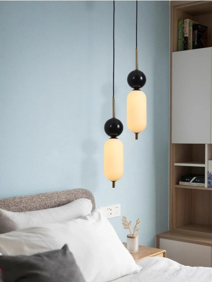 Suspension moderne bicolore boule noire marbre éclairant une pièce avec un plafonnier noir et blanc. Complément idéal pour l'éclairage intérieur.