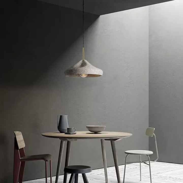 Une table et des chaises dans une pièce, suspension ciment terrazzo évasée déformée scandinave industriel. Parfaite pour illuminer votre espace avec une touche contemporaine.