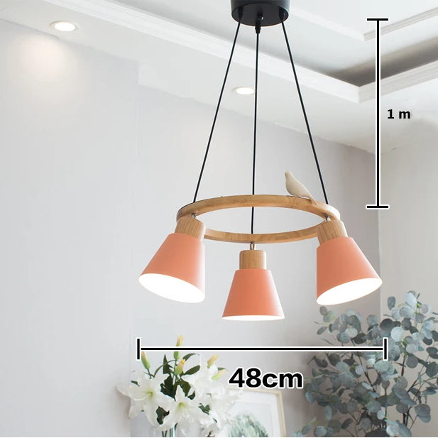 Suspension bois coloré cercle oiseau 3 lampes, éclairant un intérieur avec style scandinave contemporain.