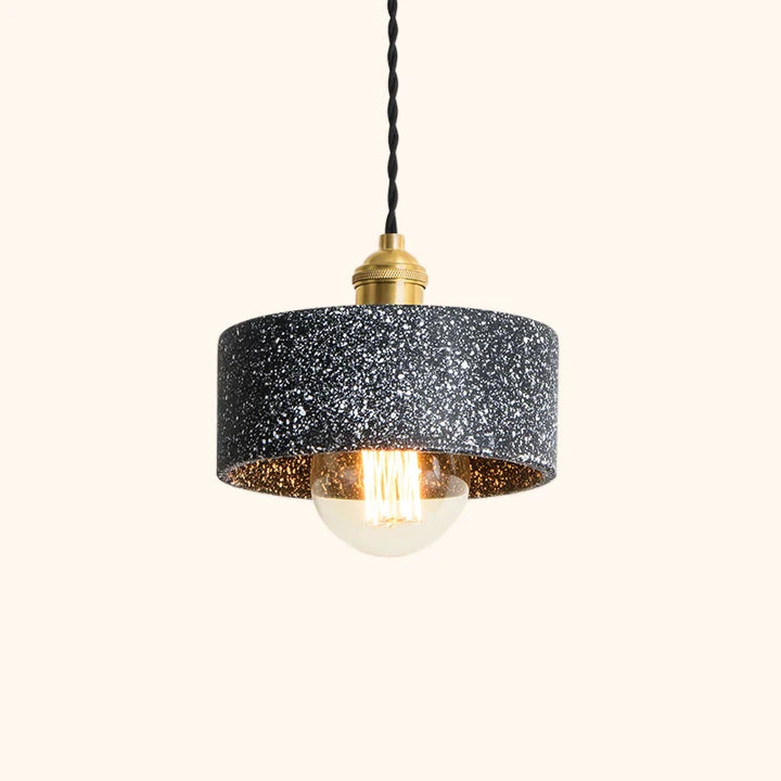 C'est une suspension effet terrazzo noir cylindrique avec un câble tressé noir et des détails dorés.