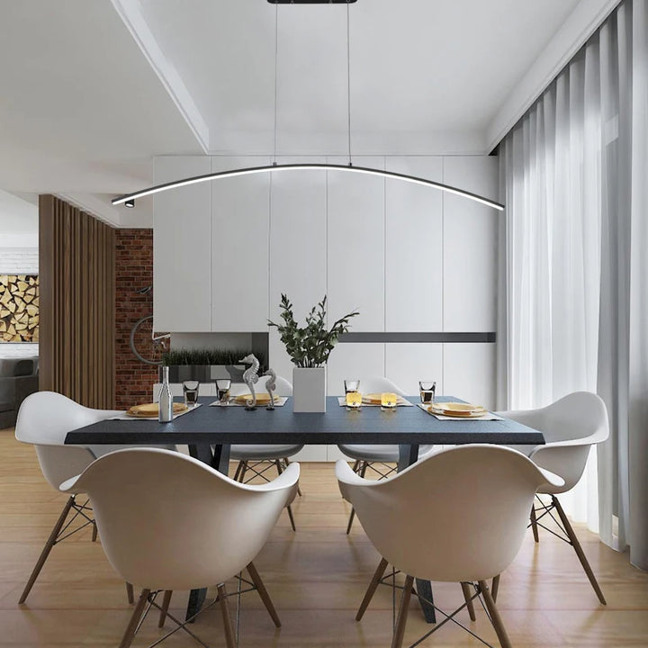 Une table à manger avec des chaises blanches dans une pièce. Une suspension métal arche design moderne au-dessus de la table, ajoutant une touche d'élégance contemporaine.