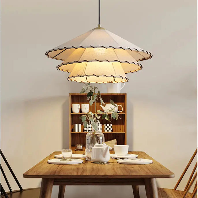 Suspension lin blanc fil noir triple triangle bohème sur une table avec une lampe et une théière. Ambiance chaleureuse et détendue pour un intérieur bohème ou éclectique.