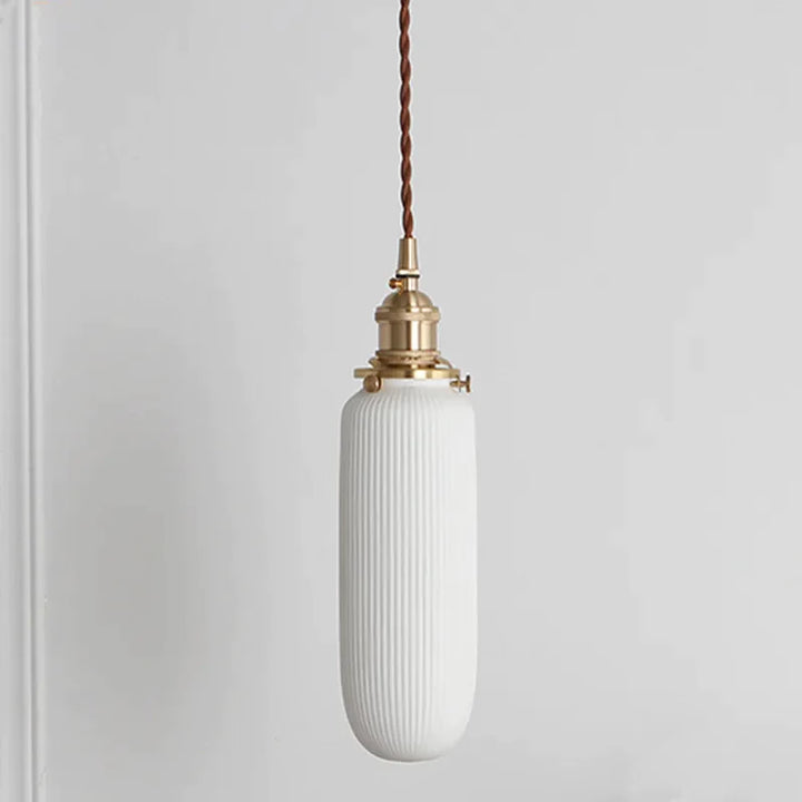 Suspension céramique blanche rainurée et cuivre allongée vintage, éclairage blanc chaud LED, idéale pour éclairer des espaces verticaux ou des coins intimistes avec un charme intemporel. Ampoule incluse. Taille disponible : 7,5x22 cm. Longueur câble : 160 cm.