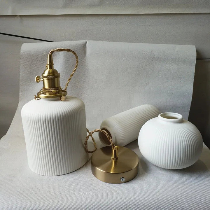 Suspension céramique blanche rainurée et cuivre cloche vintage, éclairage chaleureux pour votre décoration intérieure.