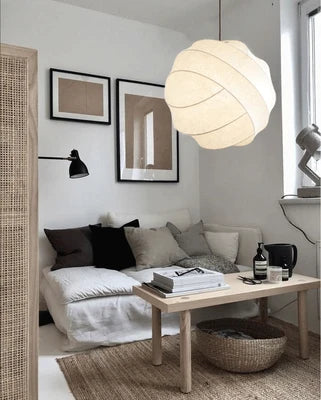 Une pièce avec un canapé, une table et une suspension sphérique en tissu soie design vintage suspendue au plafond.