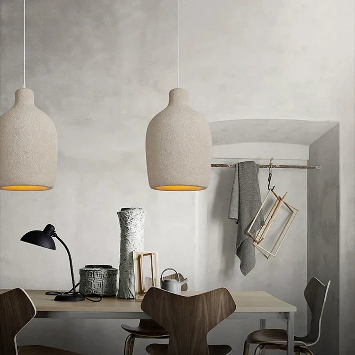 Suspension cloche en résine effet terre cuite beige bohème, entourée d'une table avec des chaises et des lampes. Ambiance chaleureuse pour votre décoration intérieure. Dimensions : 26x46 cm.